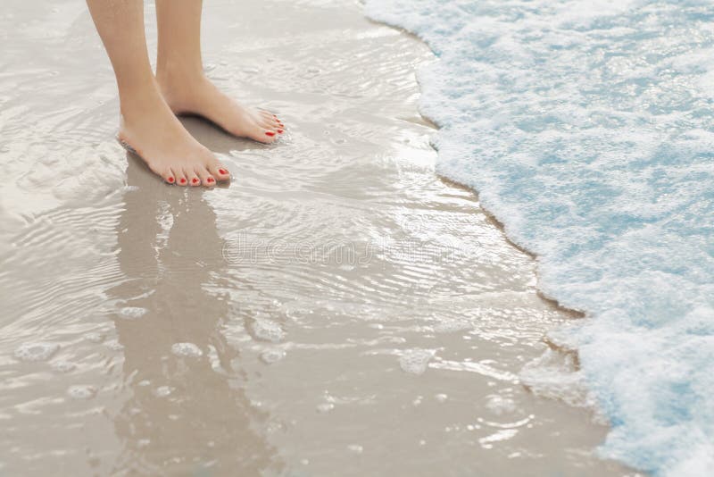 Woman`s feet standing in surf at the beach in surf. Woman`s feet standing in surf at the beach in surf