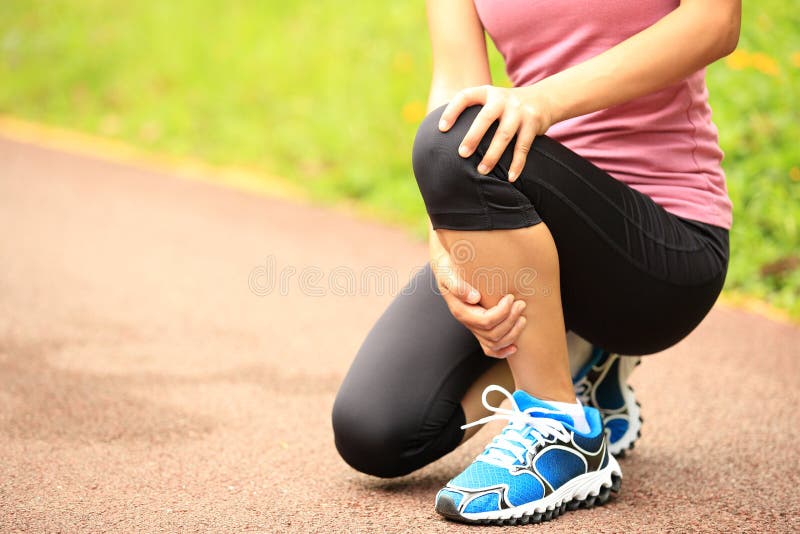 Young woman runner holder her sports injured knee. Young woman runner holder her sports injured knee