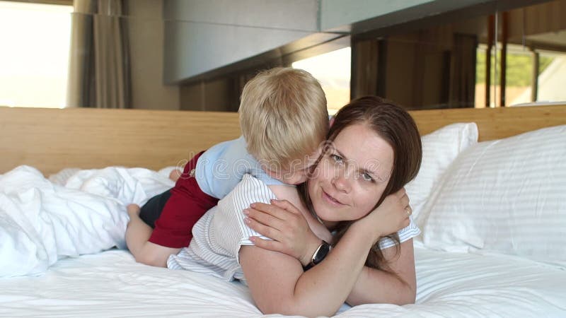 Mom and son lying in bed in the morning, the boy kissed and hugged his mother stock video. The video includes feeling, pajamas, people, yes- 167806465  