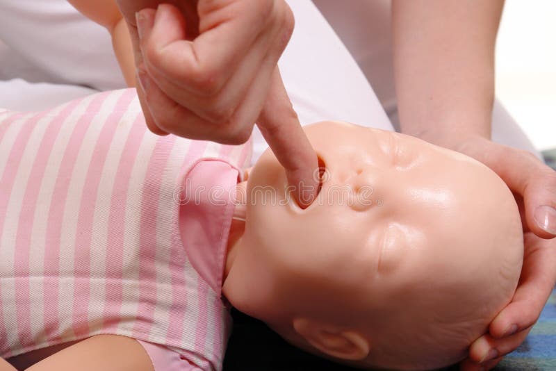 Closeup of first aid instructor using infant dummy demonstrating how to rescue a suffocating baby. Closeup of first aid instructor using infant dummy demonstrating how to rescue a suffocating baby