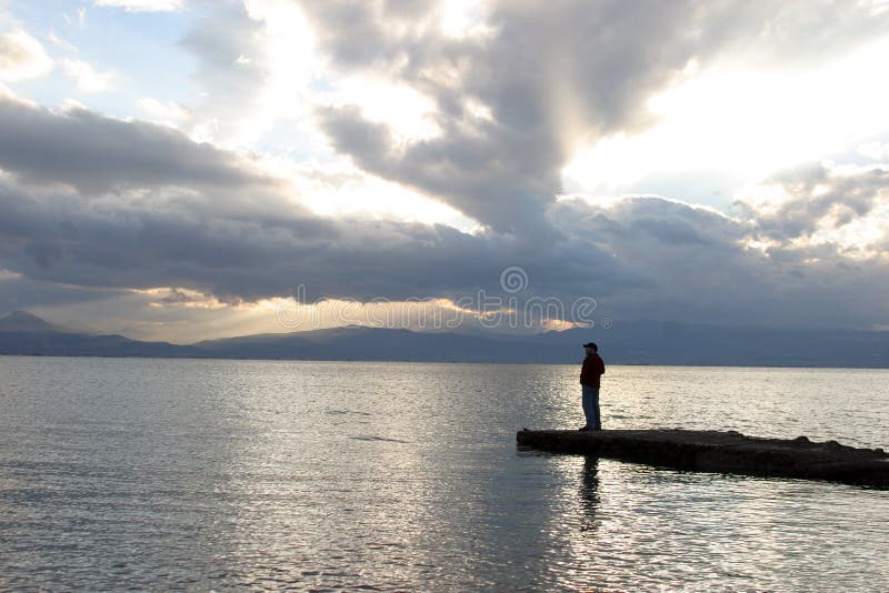 Silhouette of man standing on a peer by the sea. Silhouette of man standing on a peer by the sea