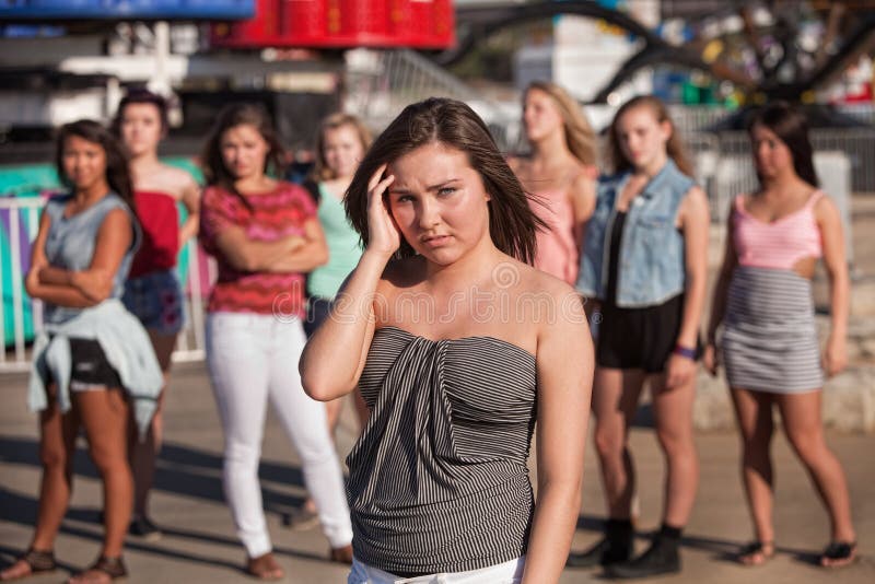 Depressed young women away from friends at amusement park. Depressed young women away from friends at amusement park