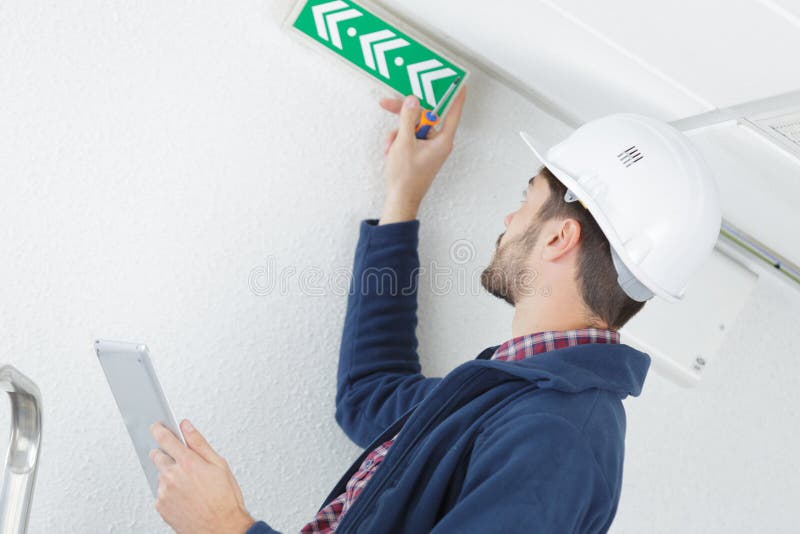 技术员正在安装紧急出口标志 库存照片