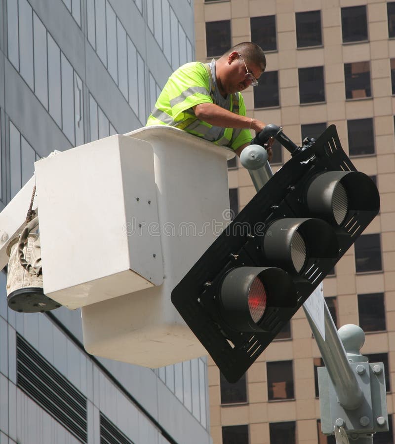 Houston, Texas - September 18, 2008: Public Safety Worker Fixing Tilted Red Traffic Light after Hurricane Ike (Editorial). Houston, Texas - September 18, 2008: Public Safety Worker Fixing Tilted Red Traffic Light after Hurricane Ike (Editorial)