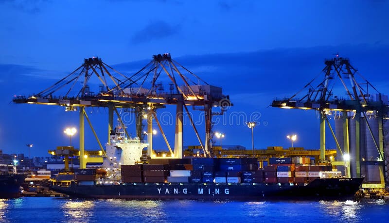 KAOHSIUNG, TAIWAN -- JUNE 2, 2019: Containers are being loaded onto ships in Kaohsiung Port at dusk. KAOHSIUNG, TAIWAN -- JUNE 2, 2019: Containers are being loaded onto ships in Kaohsiung Port at dusk