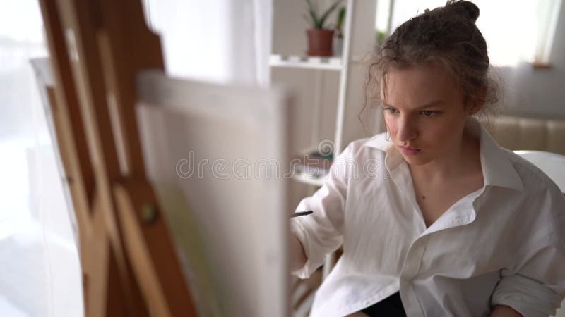 富有灵感的成功年轻艺术家的肖像,站在用笔记本电脑画画的背景上,面带微笑的相机 股票视频