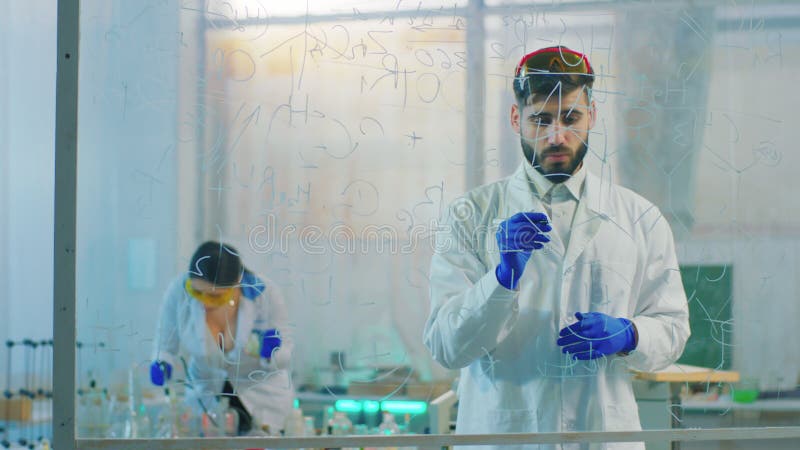 富有魅力的科学的家庭成员在使用透明委员会的生物化学实验室，写化学式为 影视素材