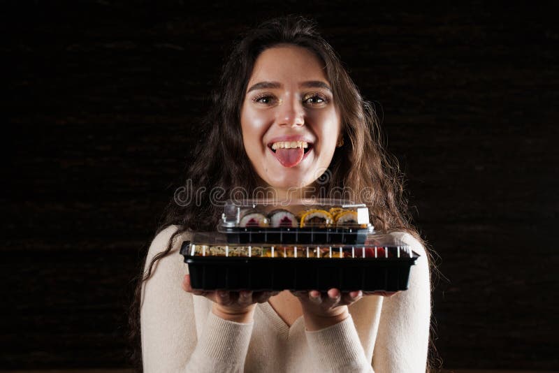 Girl with sushi. Food courier holding 2 sushi boxes . Delivery at quarantine coronavirus covid-19. Girl with sushi. Food courier holding 2 sushi boxes . Delivery at quarantine coronavirus covid-19.