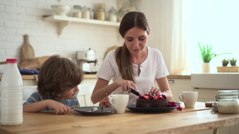 小女人切蛋糕，和孩子一起在家厨房吃饭.
