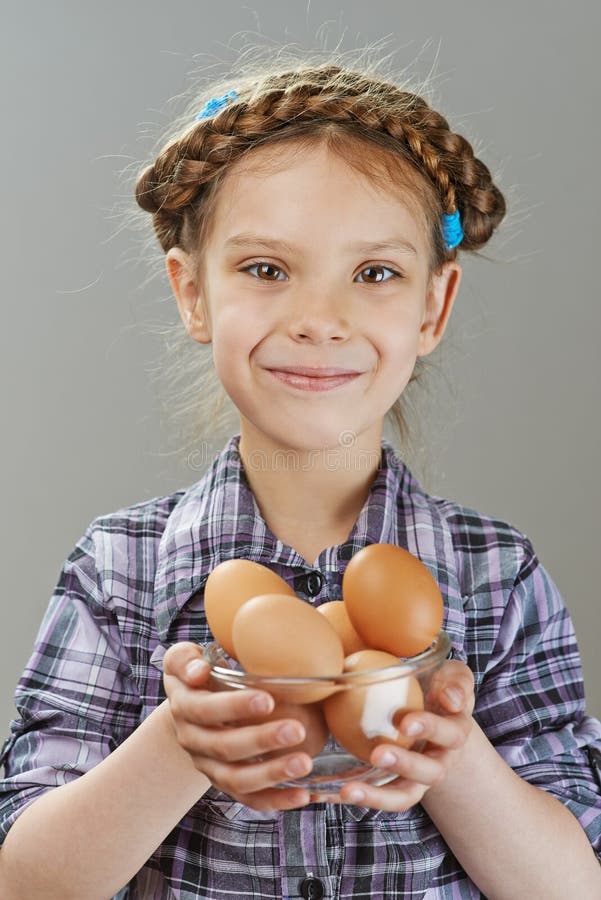 Little girl holding glass dish with chicken eggs, on gray background. Little girl holding glass dish with chicken eggs, on gray background.