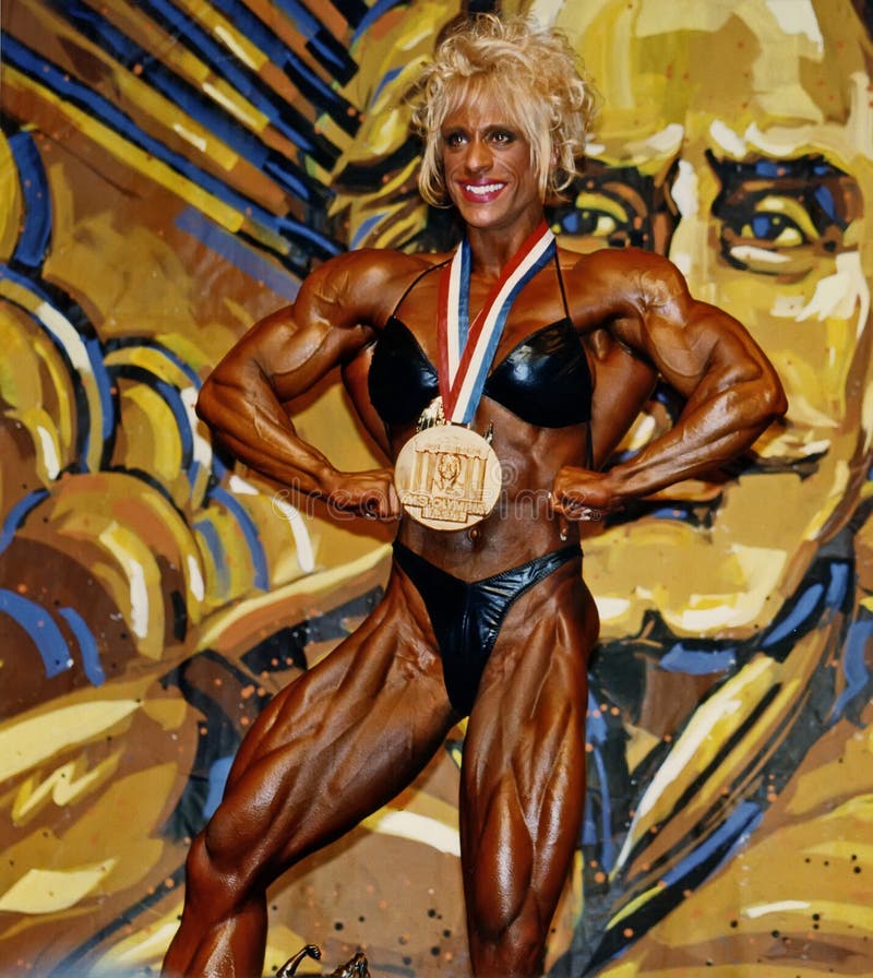 Under the watchful eye of Joe Weider &#x28;in mural&#x29;, Kim Chizevsky poses with her first place medal won in the pro women&#x27;s bodybuilding contest at the IFBB Ms Olympia in New York City on November 22, 1997. Kim amazing physique displays superb symmetry, size, and ripped definition. Under the watchful eye of Joe Weider &#x28;in mural&#x29;, Kim Chizevsky poses with her first place medal won in the pro women&#x27;s bodybuilding contest at the IFBB Ms Olympia in New York City on November 22, 1997. Kim amazing physique displays superb symmetry, size, and ripped definition.