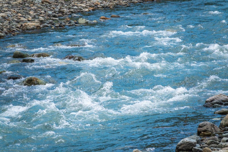 Stones in water riffle of mountain river. Powerful water stream among stones in mountain creek with rapids. Fast flow among rocks in highland brook. Small river close-up. Stones in water riffle of mountain river. Powerful water stream among stones in mountain creek with rapids. Fast flow among rocks in highland brook. Small river close-up