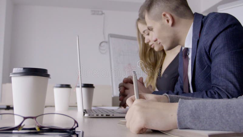 工作在与膝上型计算机的桌上的年轻雇员在现代办公室
