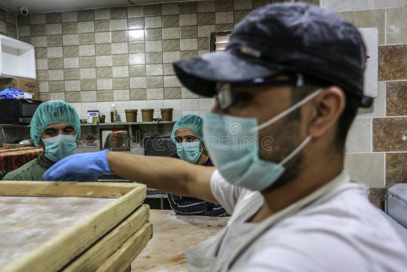 Palestinian workers wearing masks amid coronavirus precautions, bake bread at a bakery, in Rafah in the southern Gaza Strip, on March 10, 2020. Photo by Abed Rahim Khatib. Palestinian workers wearing masks amid coronavirus precautions, bake bread at a bakery, in Rafah in the southern Gaza Strip, on March 10, 2020. Photo by Abed Rahim Khatib