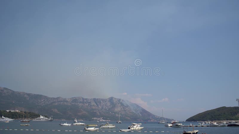 布德瓦山上的一场火，在海中游艇的背景下冒出烟