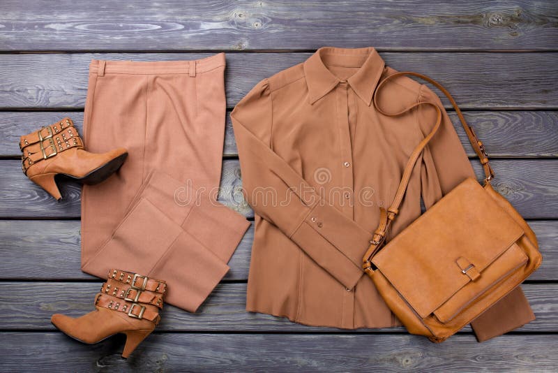 Brown female outfit flat lay. Grey wooden surface background. Brown female outfit flat lay. Grey wooden surface background.