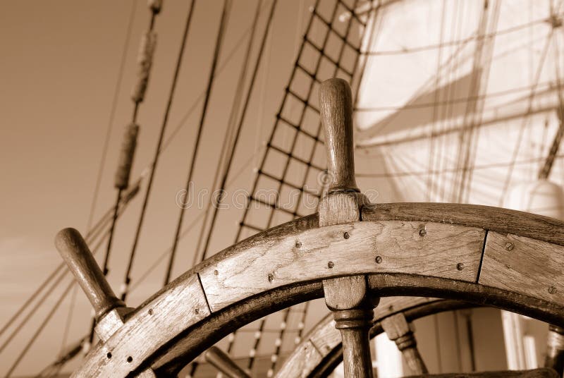 Helm of a sailing ship on the background of the sails and the ocean. Helm of a sailing ship on the background of the sails and the ocean