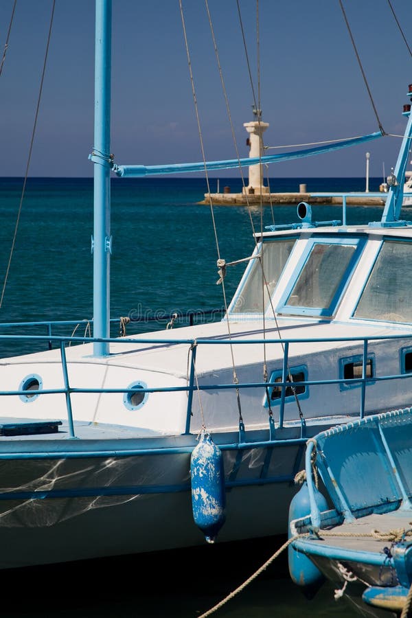 Typical Greek fishing boats are waiting in the harbor for departure. Two bronze deers guard the entrance to the Mandraki harbor. Typical Greek fishing boats are waiting in the harbor for departure. Two bronze deers guard the entrance to the Mandraki harbor.