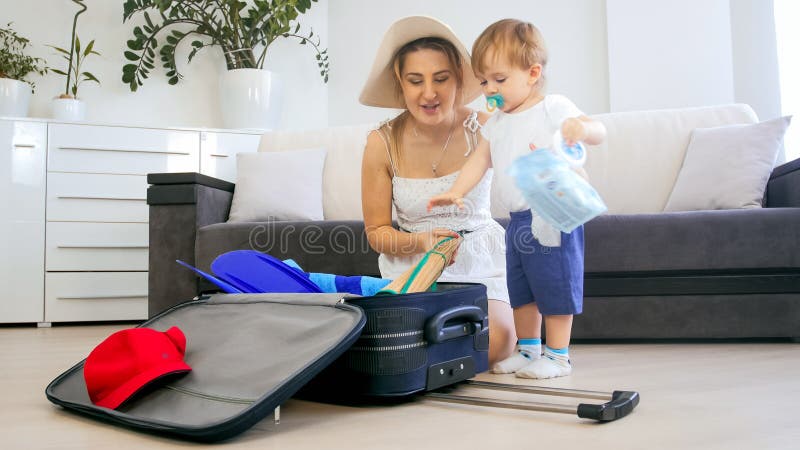 带着小孩男孩包装手提箱的美丽的年轻母亲为假期 免版税库存图片 带着小孩男孩包装手提箱的美丽的年轻母亲为假期 免版税库存图片