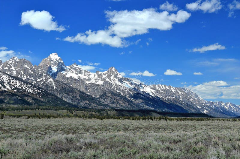 Landscape panorama of the sheer Rocky Mountains peaks of the Grand Teton Range that rise sharply above the plains at Teton Glacier Turnout in Grand Teton National Park, Wyoming, USA. Landscape panorama of the sheer Rocky Mountains peaks of the Grand Teton Range that rise sharply above the plains at Teton Glacier Turnout in Grand Teton National Park, Wyoming, USA.