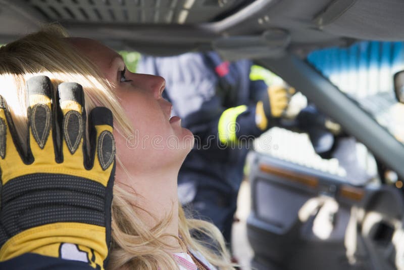 消防员正在帮助车内受伤的妇女 免版税库存图片