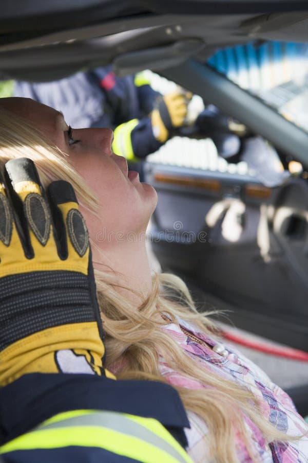 消防员正在帮助车内受伤的妇女 库存图片