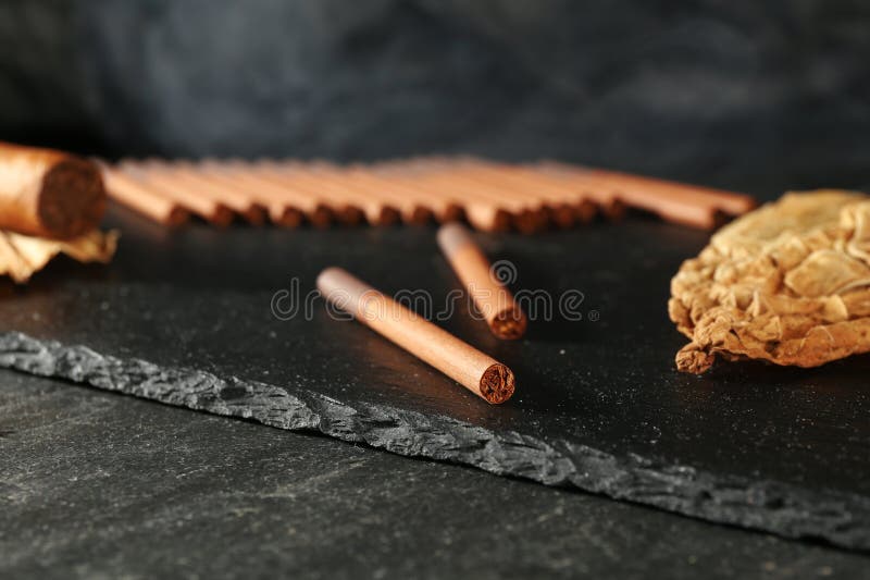 干燥的烟草叶和香烟在黑色桌面上，特写 免版税库存照片