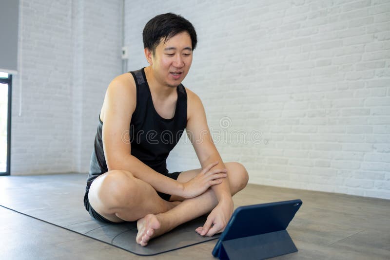 年轻人在家锻炼时观看平板电脑视频教程. 男性健身员在线训练