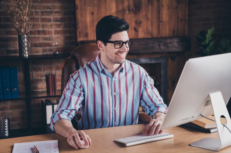 Photo of nice young corporate man use computer wear striped shirt loft interior office indoors. Photo of nice young corporate man use computer wear striped shirt loft interior office indoors.