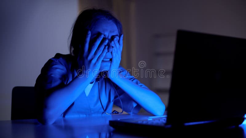 年轻医生哭泣的研究膝上型计算机,从患者,夜班损失的重音 库存图片 年轻医生哭泣的研究膝上型计算机,从患者,夜班损失的重音 库存图片