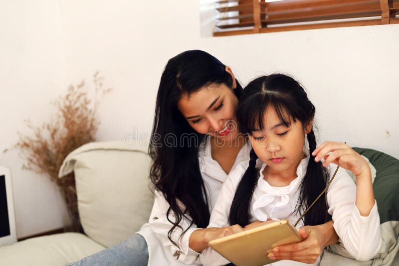 年轻女妈妈微笑着陪着女孩在家工作 库存图片 年轻女妈妈微笑着陪着女孩在家工作 库存图片