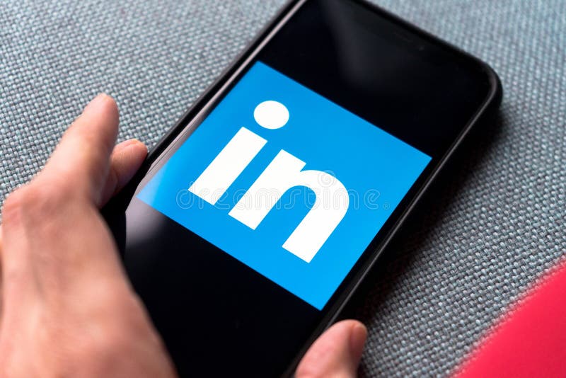 年轻女性手持一部带Linkedin应用的智能手机 库存图片 年轻女性手持一部带Linkedin应用的智能手机 库存图片