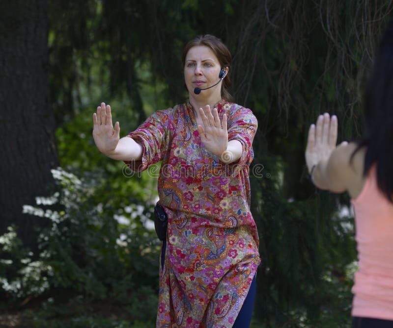 年轻女瑜伽教练展示在城市公园冥想的方式