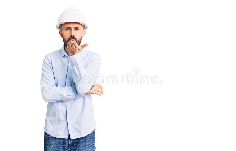 年轻帅气的男人，戴着建筑师的硬帽，看着摄像机拍下的亲吻，空气中既可爱又性感 免版税库存图片