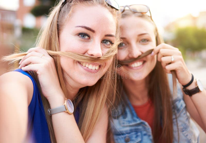 年轻快乐的千禧一代女性朋友们一起玩得很开心 - 拍一张有趣而愚蠢的自拍，戴着假发胡子 - 感受自由 库存图片
