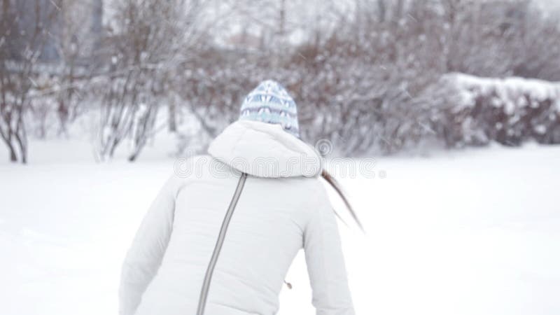 年轻快乐的女孩在冬天走在公园，使用在雪，寒冷