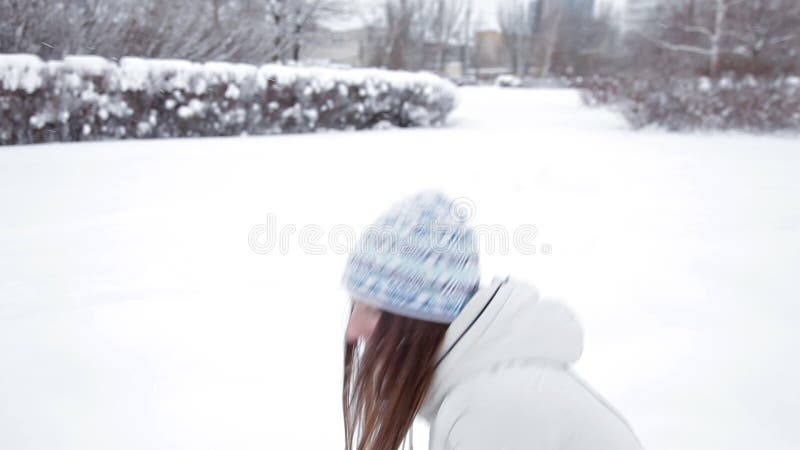 年轻快乐的女孩在冬天走在公园，使用在雪，寒冷