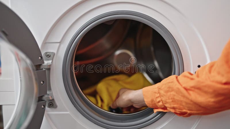 年轻漂亮的西语裔女人洗衣服在洗衣房洗衣机上放洗衣液袋