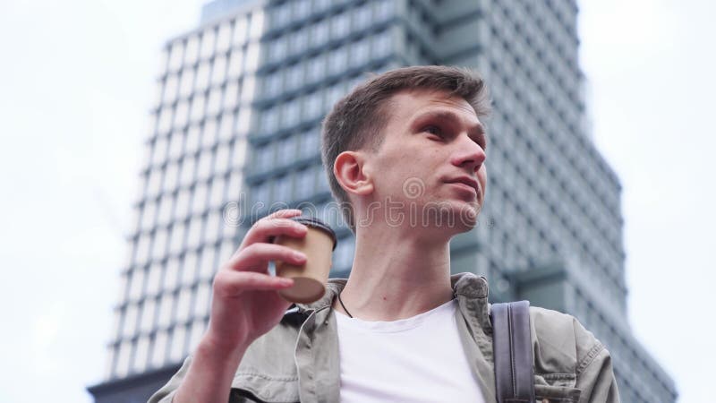 年轻的男性企业家带着智能手机和一杯咖啡在大都市漫步.
