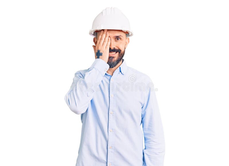 年轻的覆盖率一意见帅哥的建筑师安全帽戴在脸上和惊喜情绪的手自信的微笑 免版税库存照片