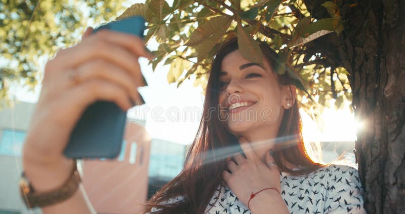 年轻美丽的浅黑肤色的男人的特写镜头画象有俏丽的采取在机动性的微笑和自然构成的selfie