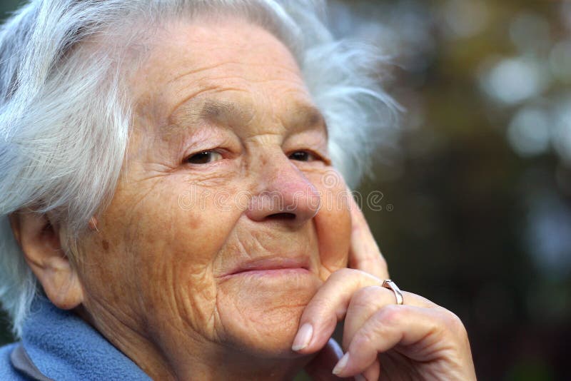 An elderly - 89 year old - woman looking into the camera and smiling. Shallow DOF. An elderly - 89 year old - woman looking into the camera and smiling. Shallow DOF.