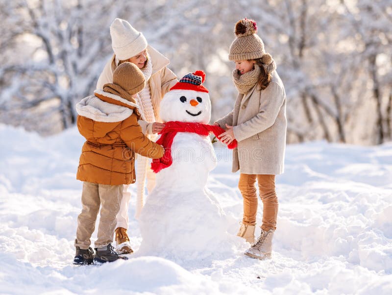幸福的家庭母亲和两个小孩在冬季公园外面一起做雪人