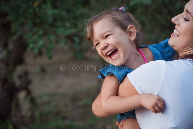 幼母幼女在园林中的活动 一个快乐的小女孩在母亲手中 免版税库存图片