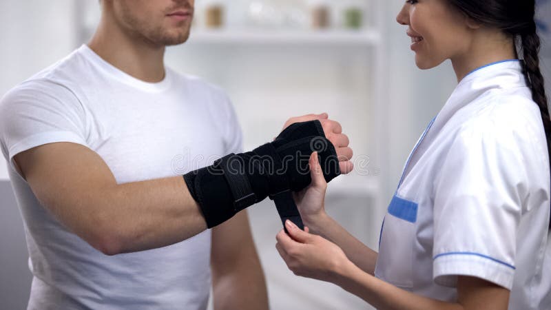 应用巨人腕子括号男性患者,修复的微笑的女性外科医生 免版税库存照片 应用巨人腕子括号男性患者,修复的微笑的女性外科医生 免版税库存照片