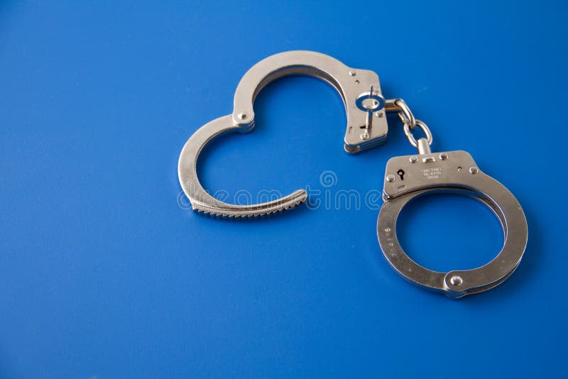 Open handcuffs with key on a blue background. Open handcuffs with key on a blue background.