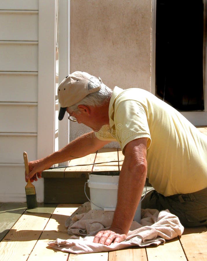 Close up shot of man brushing on deck stain. Close up shot of man brushing on deck stain