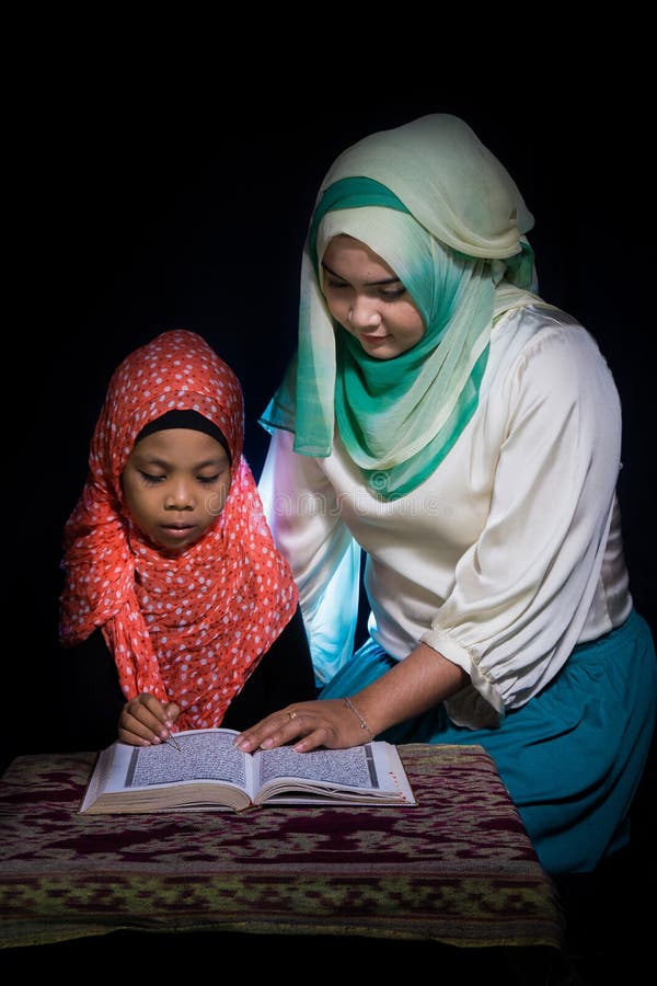 弗洛勒斯,INDONESIA-JUNE 25 2014年:hijab姐妹教在一张桌也佩带hijab读古兰经的她的姐妹 免版税库存照片 弗洛勒斯,INDONESIA-JUNE 25 2014年:hijab姐妹教在一张桌也佩带hijab读古兰经的她的姐妹 免版税库存照片