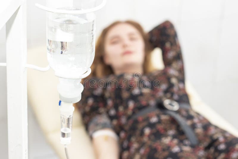 当他们为治疗在屋子hospita里时,来盐滴水特写镜头与背景妇女患者的在床上更好变 库存照片