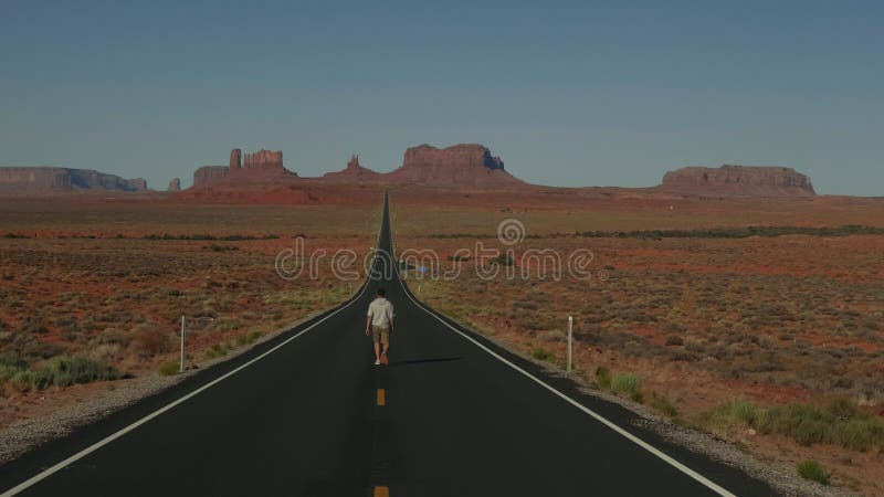 影片背景中的男人走向地平线，在纪念碑谷的壮丽的沙漠高速公路上.